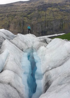 woman standing next to a crystal blue water pool on a glacier hike on falljokull outlet glacier in iceland
