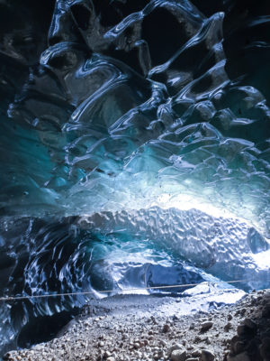 the insides of a magical blue ice cave, a rope is stretched over the back part of it.